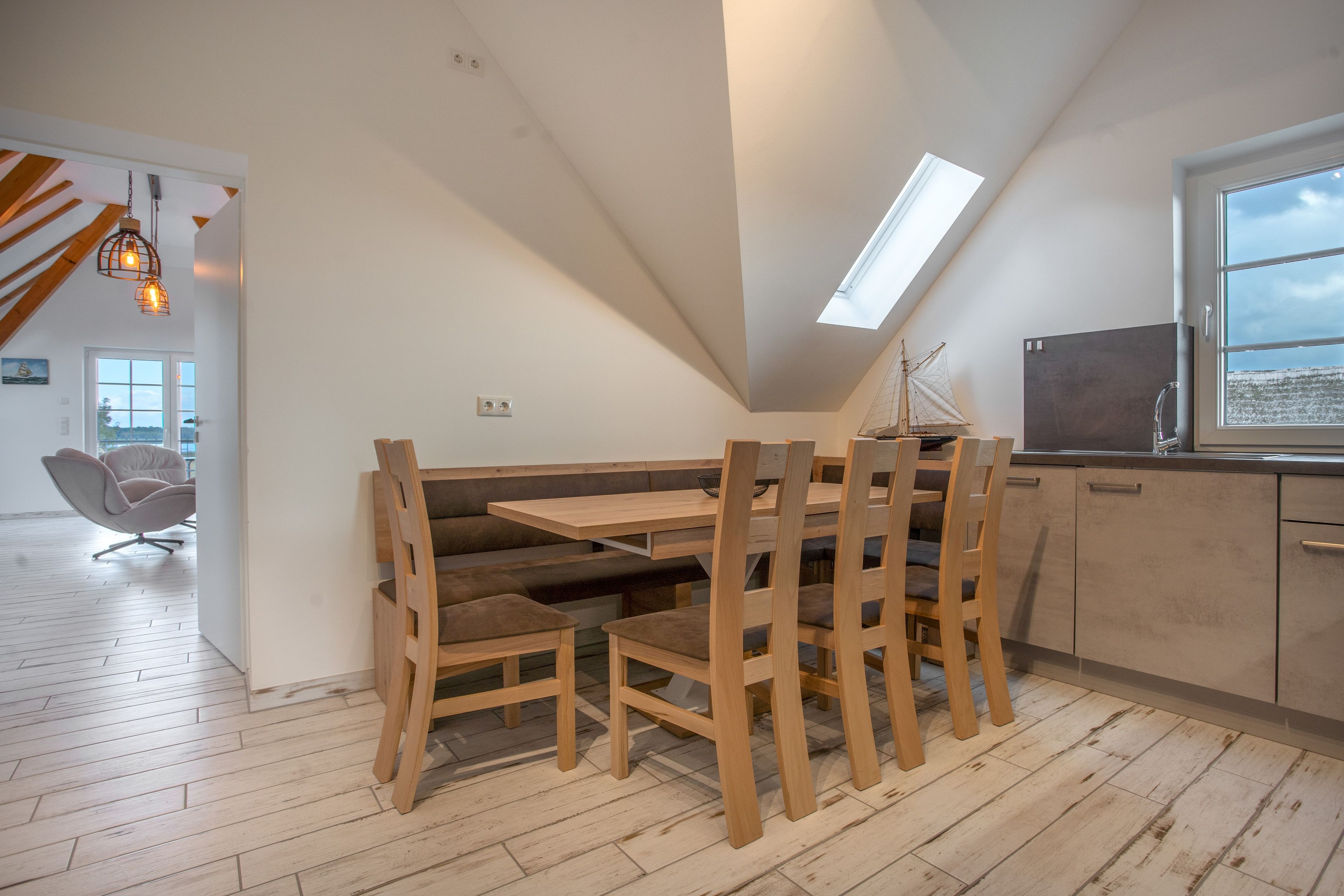 Eine moderne Küche mit einem Holzespeisetisch und Stühlen, einem Fenster mit Blick und einem Oberlicht.
