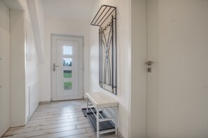 A hallway with a white door, a bench, and a metal rack on the wall. - Apartment "Haus Peenestrom" with Sea View, Private Garden, and Wi-Fi (Kröslin)