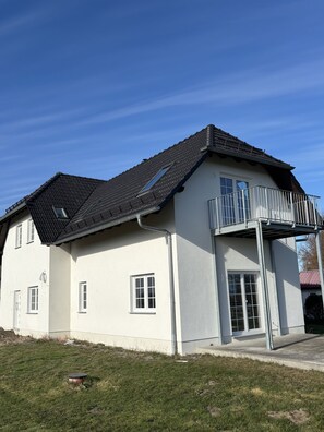 A two-story building with a balcony, a window, and a door.