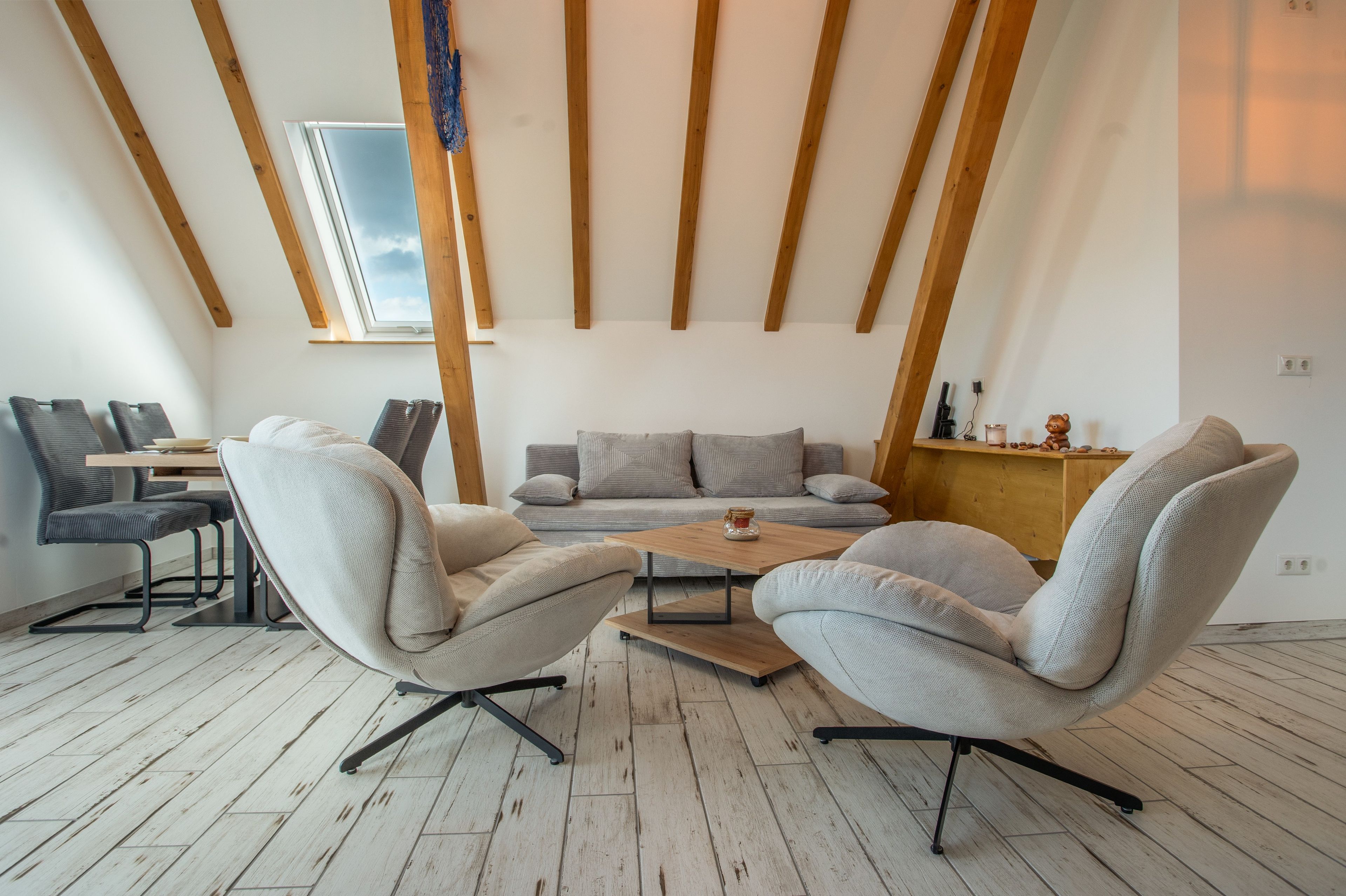 Una sala de estar moderna con un conjunto de sofás, una mesa de centro y un comedor con sillas y una mesa.