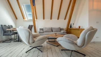 Ein modernes Wohnzimmer mit einer Sofagarnitur, einem Couchtisch und einem Essbereich mit Stühlen und einem Tisch.