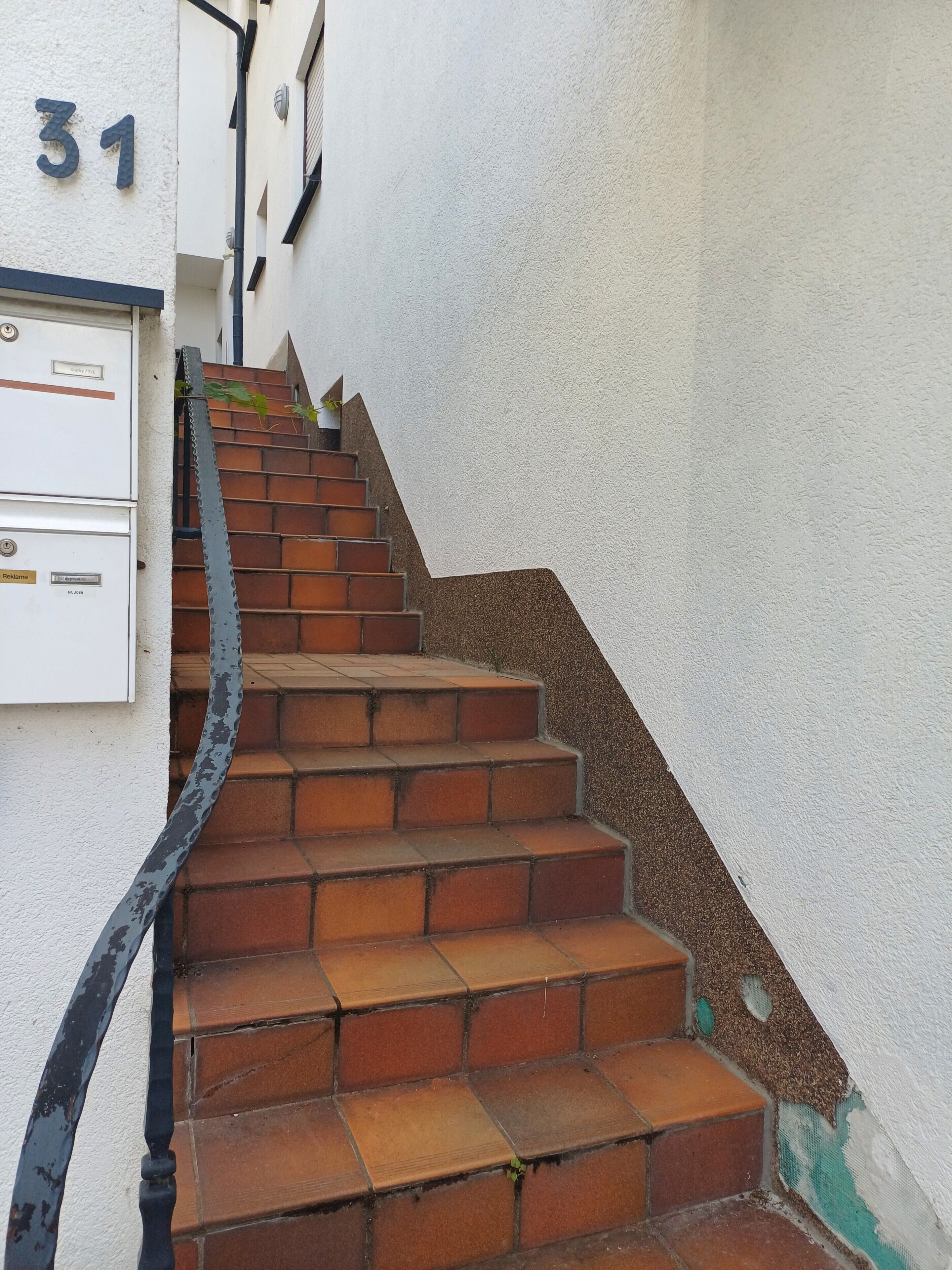 Una escalera con barandilla de metal que lleva a un rellano.