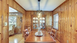 Una sala da pranzo con rivestimenti in legno, un tavolo grande, sedie e un lampadario.