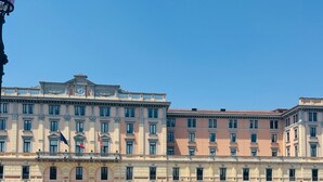 Un canale con imbarcazioni ormeggiate, un edificio dall'architettura classica e un cielo azzurro limpido.