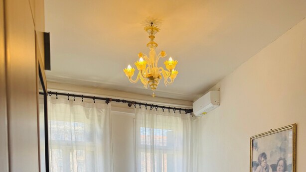 A hotel room with two beds, a chandelier, a painting, and a window with curtains. - Double Room 3 with Wi-Fi and Air Conditioning (Venice)