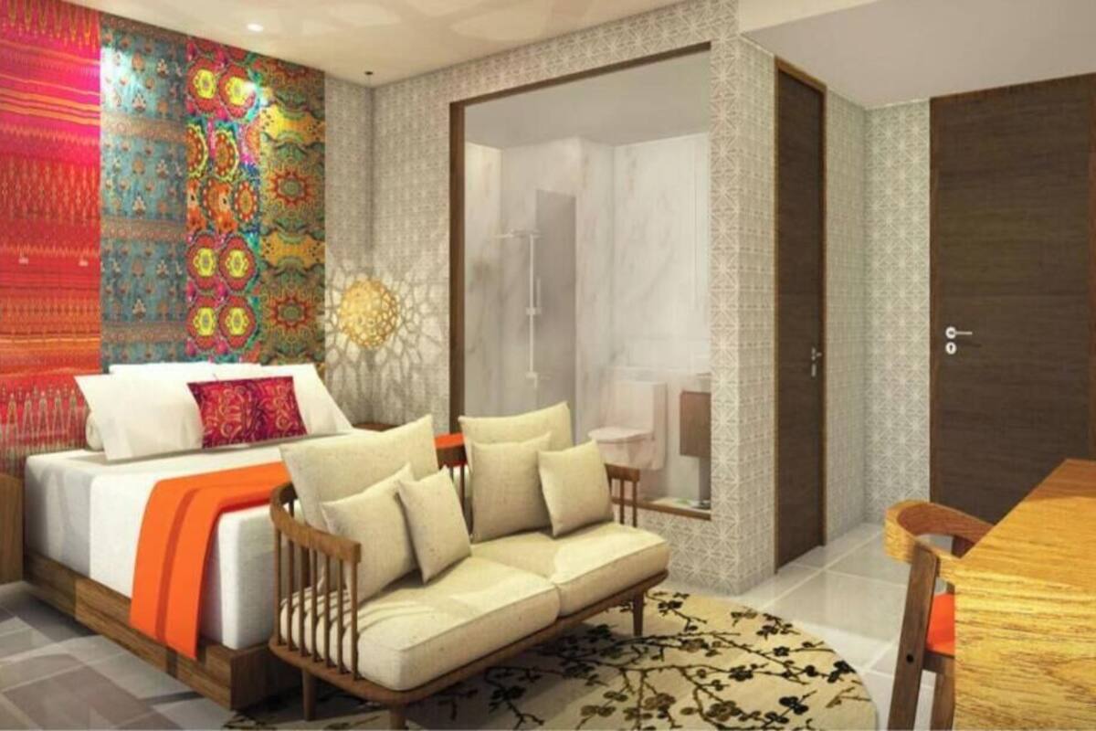 Quarto moderno com cama, sofá e chuveiro em vidro.