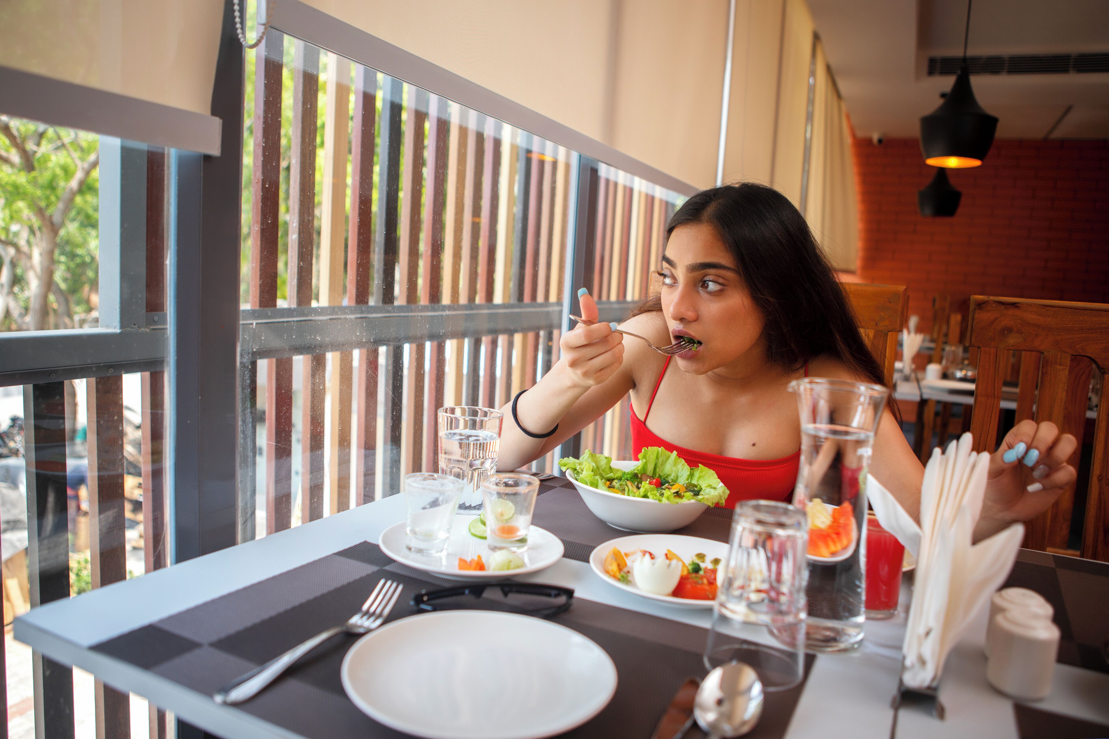 Een eettafel met een salade, waterglazen, een bord en bestek.