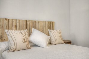 A bed with a wooden headboard, two pillows with a leaf pattern, and a quilted bedspread. - Villa Pinar in Conil with Private Pool, Wi-Fi, and Air Conditioning (Conil de la Frontera)