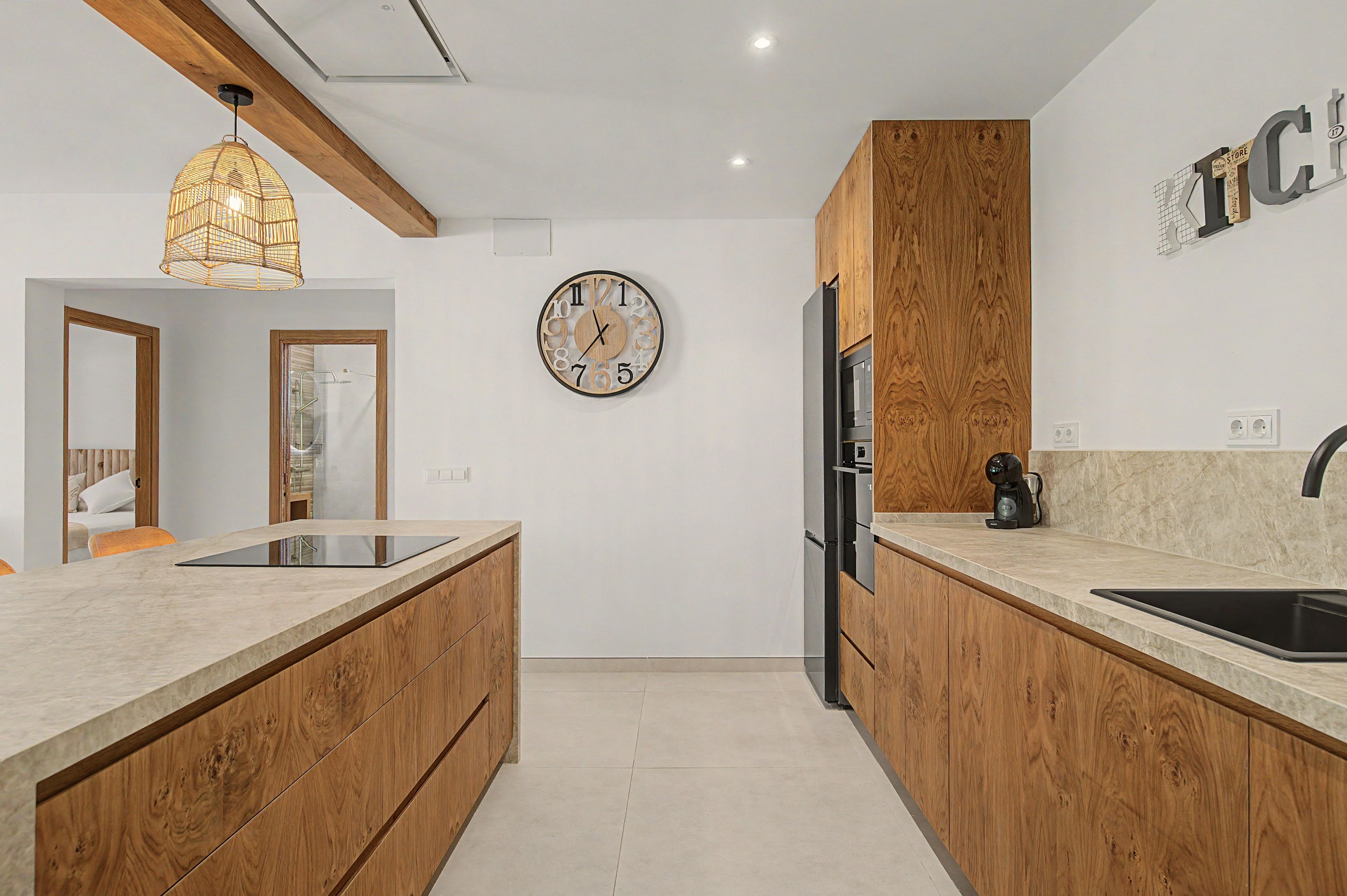 A modern kitchen with wooden cabinetry, a central island, a built-in refrigerator, and a coffee maker on the countertop.