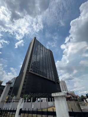 A tall, modern building with a glass facade, surrounded by a concrete fence. - Majestic Residence KLCC (Kuala Lumpur)