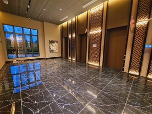 A spacious lobby with a polished black marble floor, large windows, and a wall-mounted American flag. - Majestic Residence KLCC (Kuala Lumpur)