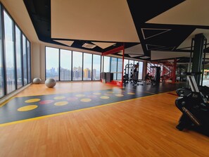 A gym with large windows, exercise equipment, and a wooden floor with colorful markings. - Majestic Residence KLCC (Kuala Lumpur)