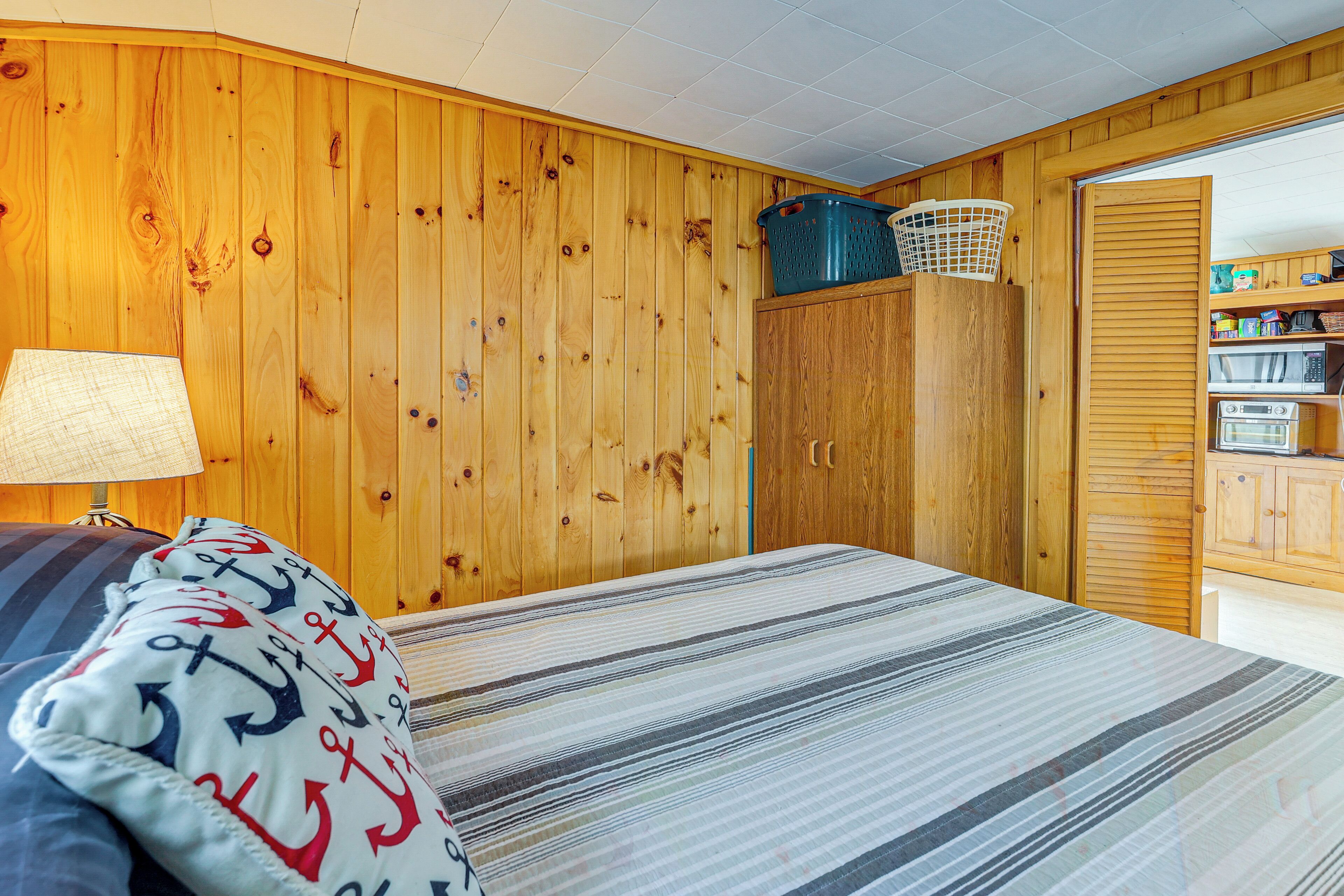 A wooden-paneled room with a bed, a lamp, and a storage cabinet.