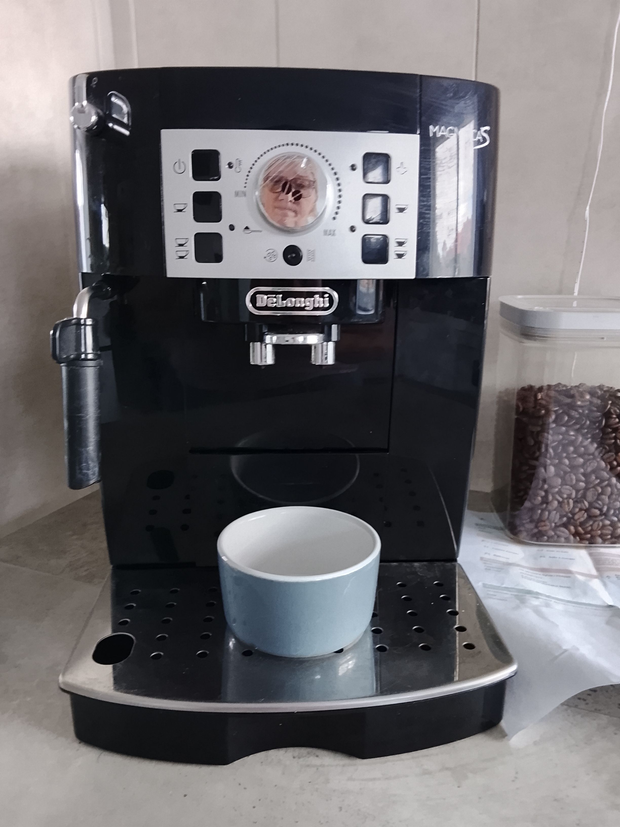 Een DeLonghi espressomachine met een kopjeshouder en een container voor koffiebonen.