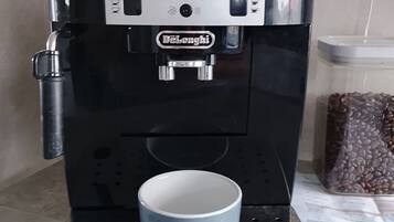 Een DeLonghi espressomachine met een kopjeshouder en een container voor koffiebonen.