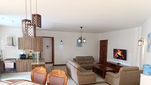 Una sala de estar moderna con sofá, televisor y comedor.