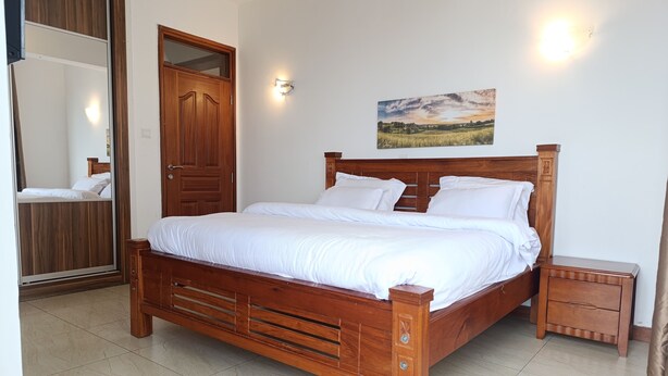 Un dormitorio con una cama de madera, un armario, un espejo y un cuadro en la pared.