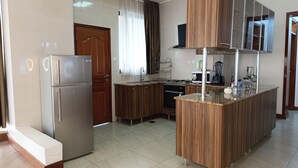 Una cocina moderna con refrigerador integrado, armarios de madera, una isla central y una ventana con cortinas.