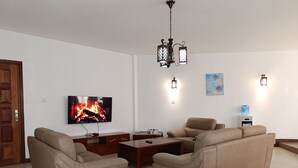 Una sala de estar con televisión, sofá, mesa de centro y chimenea.