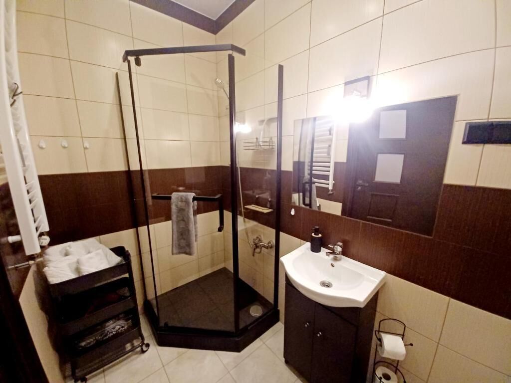 Een badkamer met een douchecabine van glas, een wastafel en een spiegel.