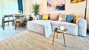 Un salon moderne avec un canapé, une table basse et un coin repas avec des chaises.