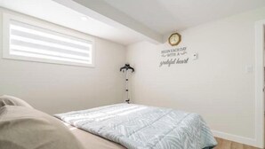 Ein Schlafzimmer mit Bett, Wanduhr, Kleiderständer und einem motivierenden Zitat.