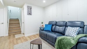 Ein Wohnzimmer mit einer Couch, einem kleinen Tisch, einer Treppe und einer Tür.