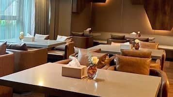 A modern restaurant with leather seating, tables, and a warm ceiling design.