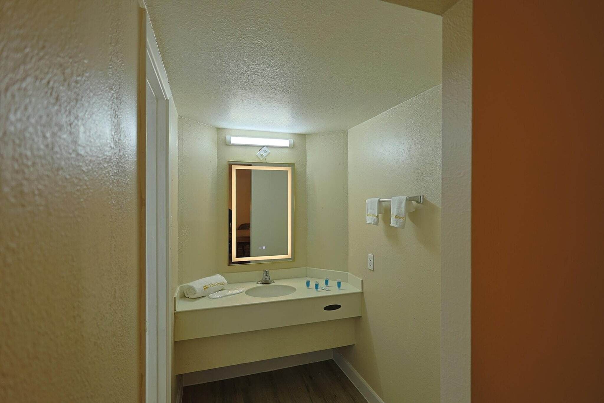 A small bathroom with a single sink, mirror, and towel rack.