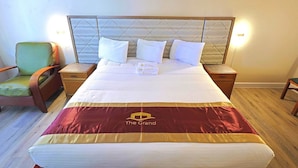 Una habitación de hotel con una cama grande, una mesita de noche, una silla y una lámpara de pared.