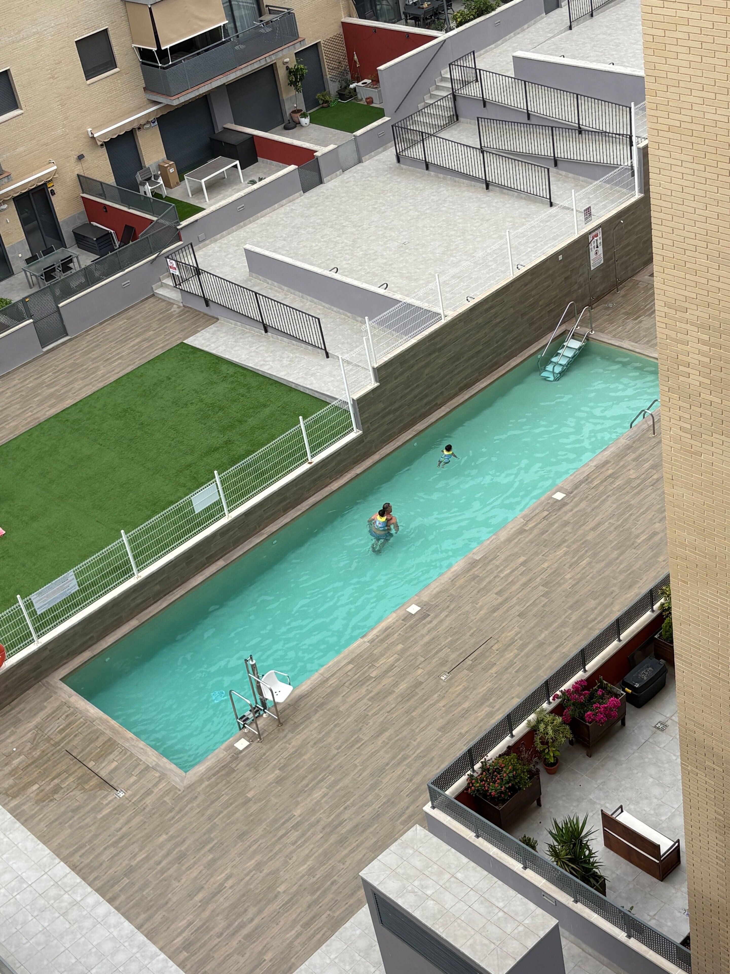 Vista aérea de una piscina en la azotea con un pequeño espacio verde y algunas plantas en macetas.