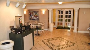 A reception area with a counter, chairs, a painting, and a patterned floor.