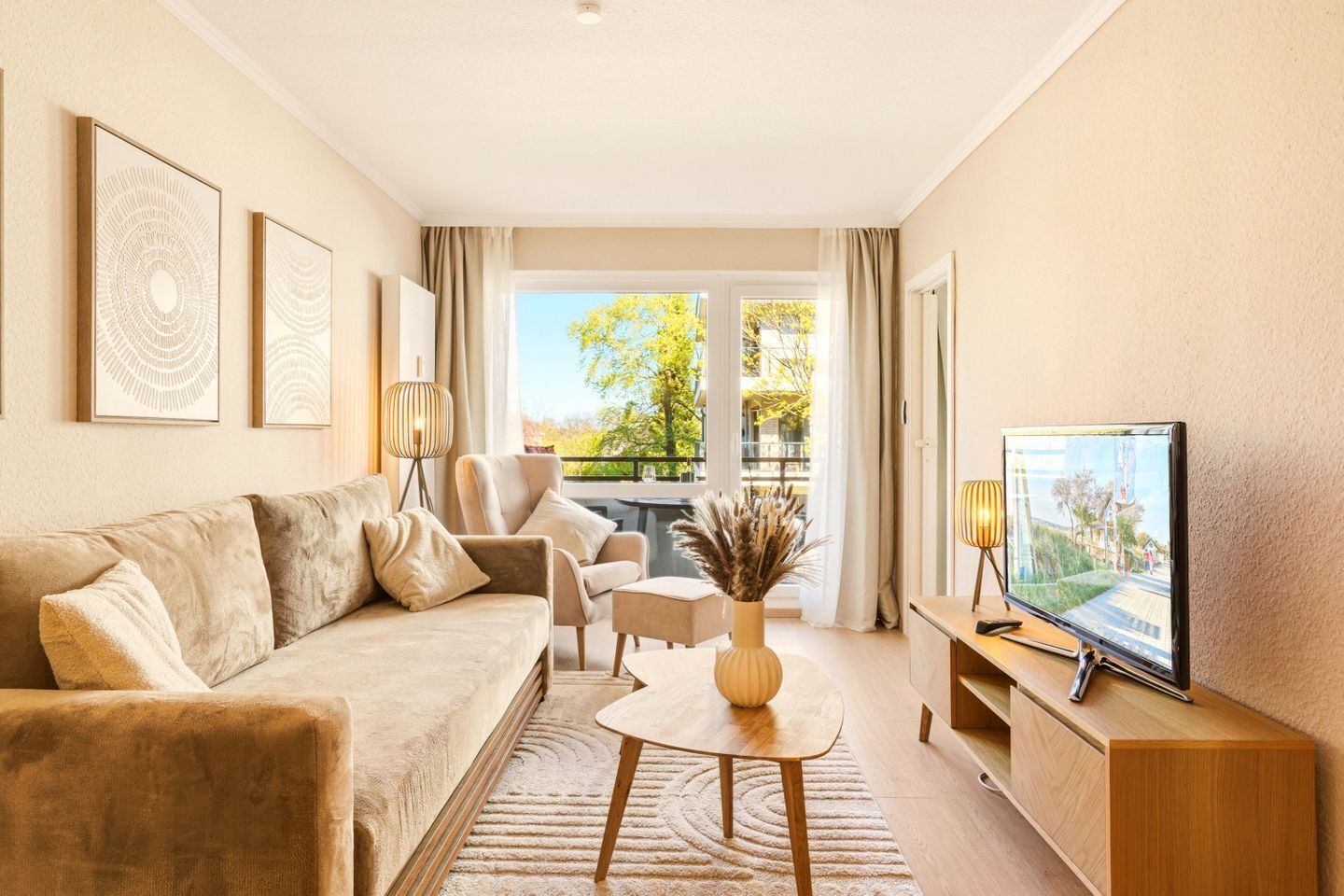 Uma sala de estar moderna com sofá, poltrona, mesa de centro, televisão e varanda com vista.