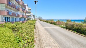 A multi-story hotel with balconies, a paved walkway, and a view of the sea. - Arrive, take a deep breath, enjoy—Apartment LichtSpiel - Residenz am Hang (Scharbeutz)