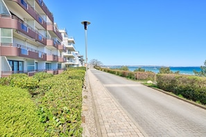 A multi-story hotel with balconies, a paved walkway, and a view of the sea. - Arrive, take a deep breath, enjoy—Apartment LichtSpiel - Residenz am Hang (Scharbeutz)