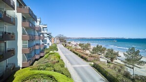 A multi-story residential building with balconies, a road leading to the beach, and a clear view of the ocean. - Arrive, take a deep breath, enjoy—Apartment LichtSpiel - Residenz am Hang (Scharbeutz)