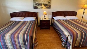 A room with two beds, a nightstand with a lamp, and a painting on the wall. - 2 Double Beds|Non-Smoking (Cadiz OH)
