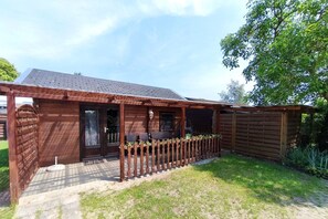 Eine Holzhütte mit Veranda, Tür und Fenster.