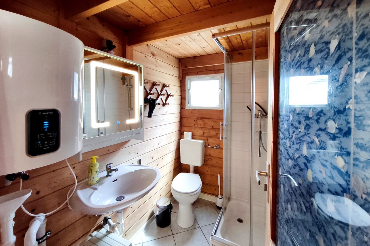 A bathroom with a white sink, a toilet, a shower, and a mirror with lights.