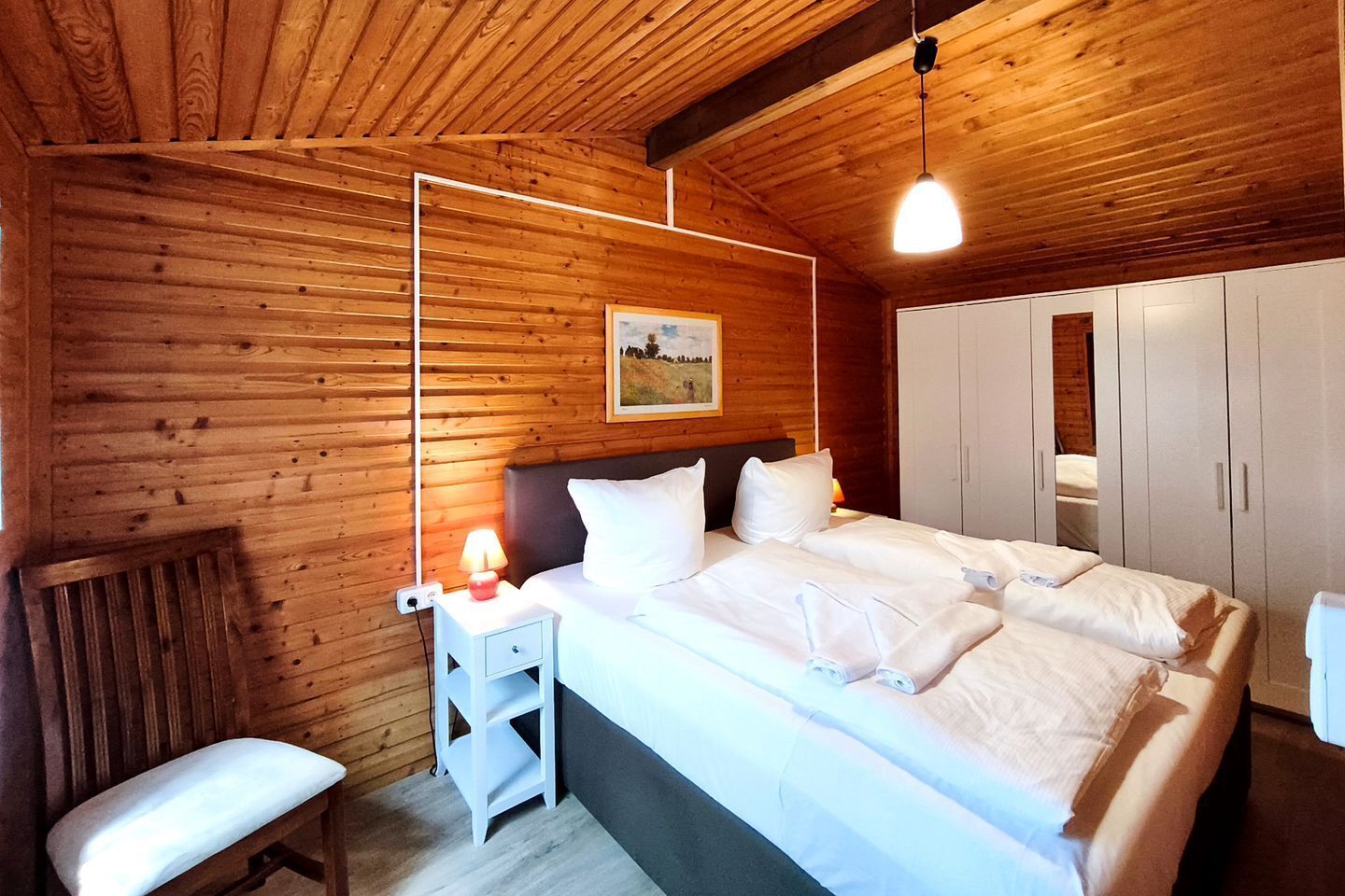 Habitació amb panells de fusta, un llit, una taula de nit, una panxa i un armari.