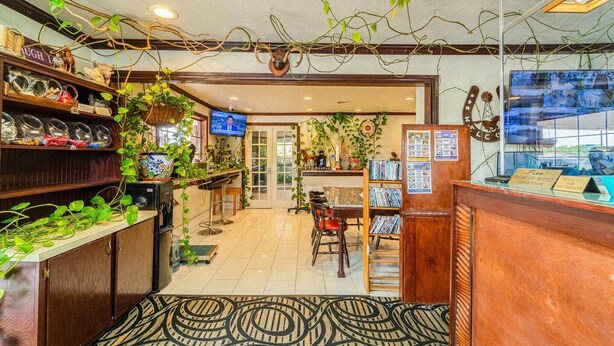 A hotel lobby with a reception desk, a television, and various plants. - 2 Queen Bed | Smoking (Snyder TX)