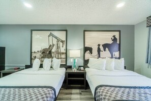 Habitación de hotel con dos camas, una mesita de noche con lámpara y dos cuadros en la pared.