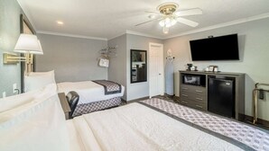 A hotel room with two beds, a ceiling fan, a TV, a minibar, and a bathroom. - 2 Queen Bed | Smoking (Snyder TX)