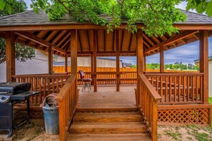 A wooden deck with a pergola, a grill, and a trash can. - 2 Queen Bed | Smoking (Snyder TX)