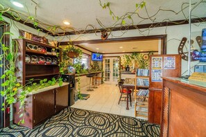 Een gezellig interieur met een houten receptiebalie, een televisie en diverse planten.