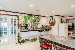 Una cocina con encimera de mármol, refrigerador y comedor con sillas.