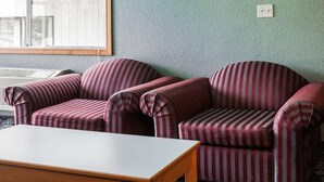 A room with two striped armchairs, a wooden table, and a window with blinds. - King Bed Non-Smoking with Jetted Tub (Stevenson WA)