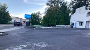 A parking lot with a white fence, a blue building, and a black car. - King Bed Non-Smoking with Jetted Tub (Stevenson WA)