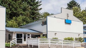 A two-story building with a porch, a small office, and a fenced parking area. - King Bed Non-Smoking with Jetted Tub (Stevenson WA)