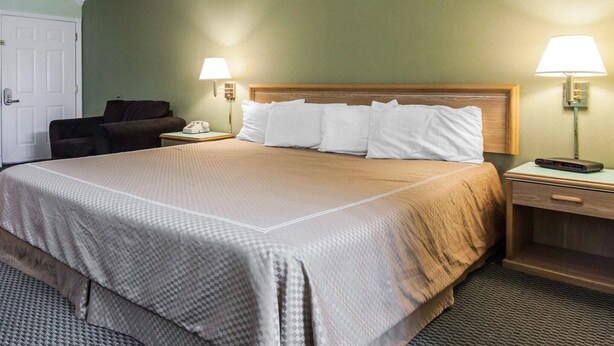A hotel room with a large bed, two bedside tables, a chair, and two wall lamps. - Full Bed Non-Smoking (Stevenson WA)